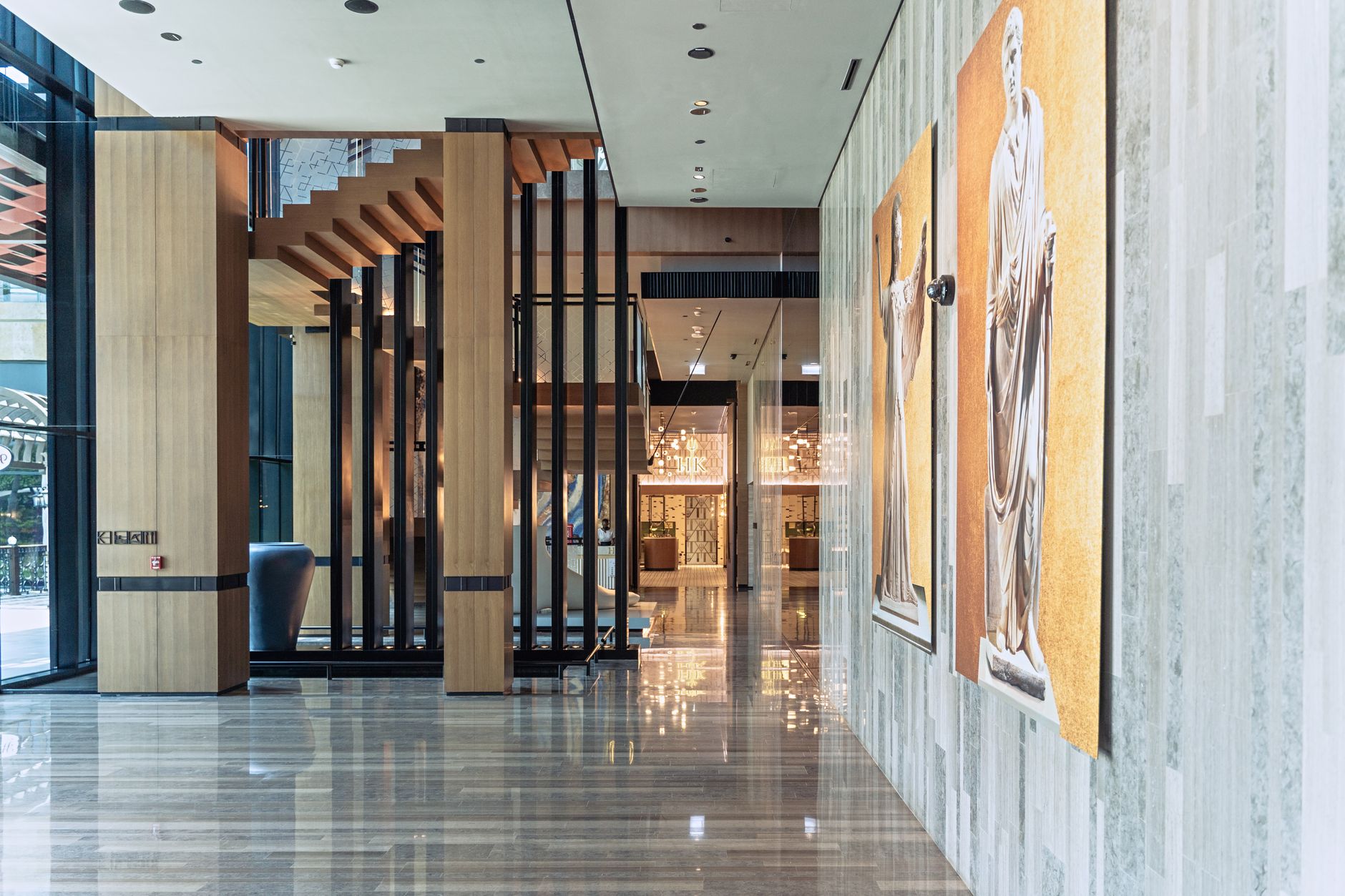 Hall intérieur spacieux d’un hôtel moderne avec sol en marbre et colonnes en bois.