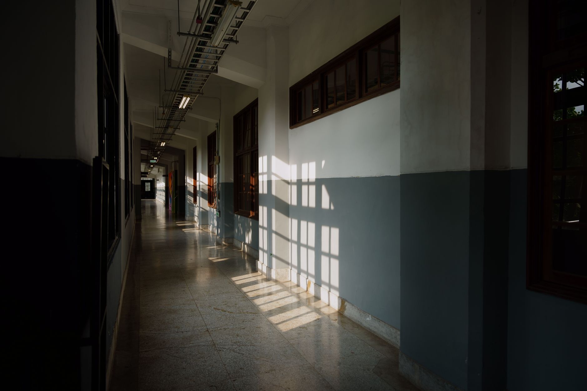 Un long couloir d'école faiblement éclairé, aux portes de classe alignées.